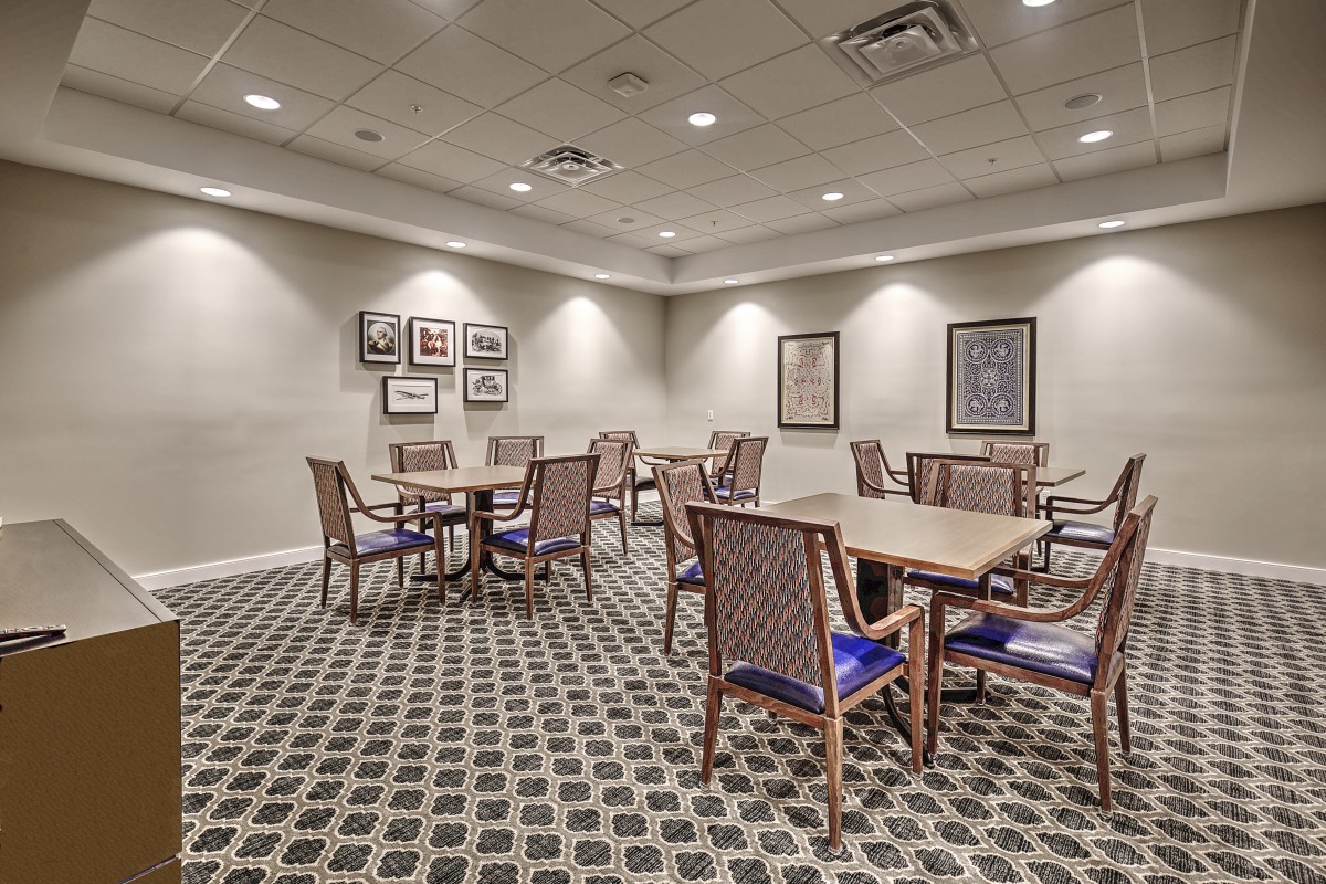 A conference room with tables and chairs set in a carpeted space, featuring artwork on the walls.