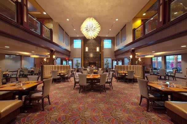 Spacious and elegant restaurant interior with a grand chandelier and neatly arranged tables.
