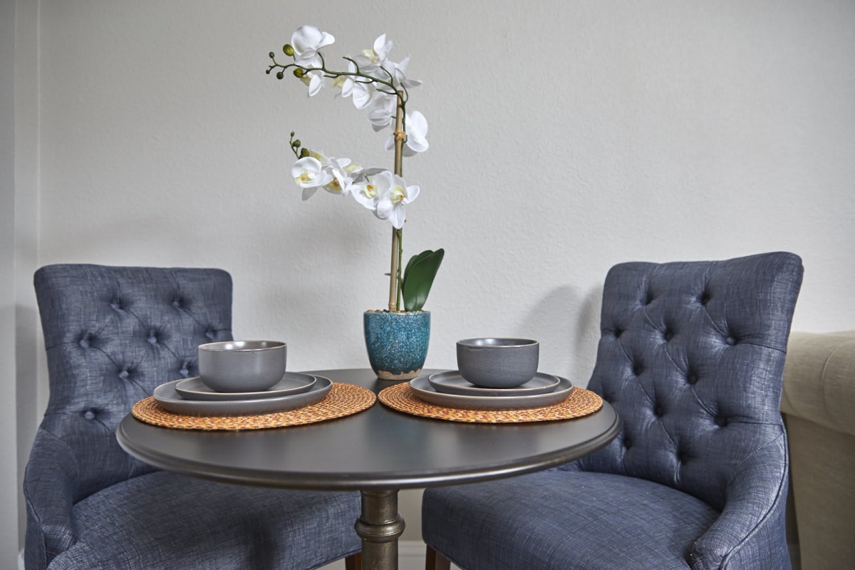 A stylish dining setup with an orchid centerpiece and gray tableware on a round table.