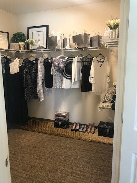 A neatly organized closet with clothes hanging and shoes arranged on the floor.