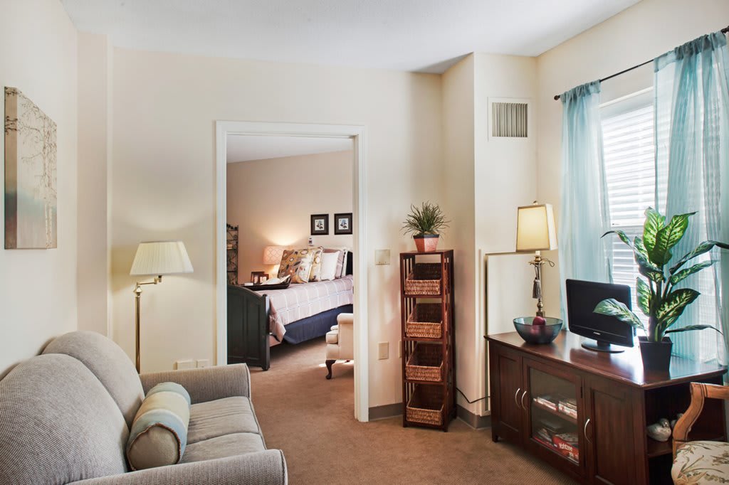 A cozy living area opens into a bedroom, featuring comfortable furniture and homey decor.