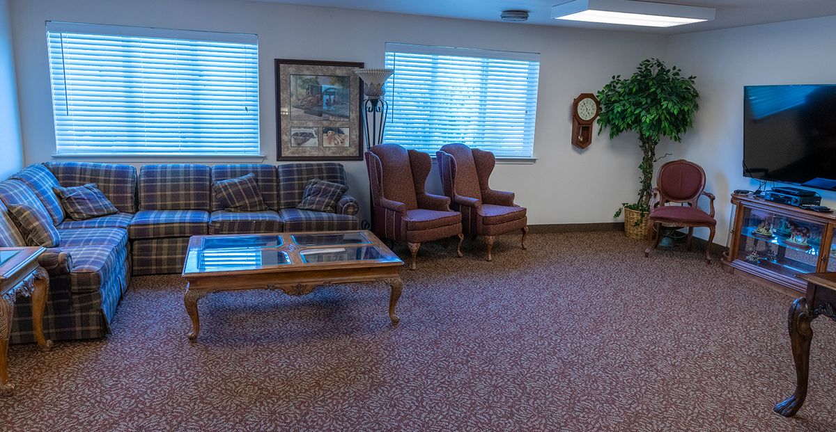 A waiting room with a sofa, chairs, and coffee table arranged on a carpeted floor.