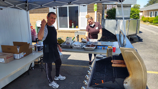 A lively barbecue scene with two people preparing food outdoors.