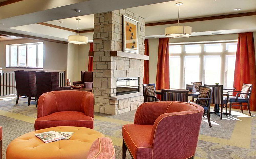 A cozy living room with modern decor featuring a central stone fireplace and comfortable seating.