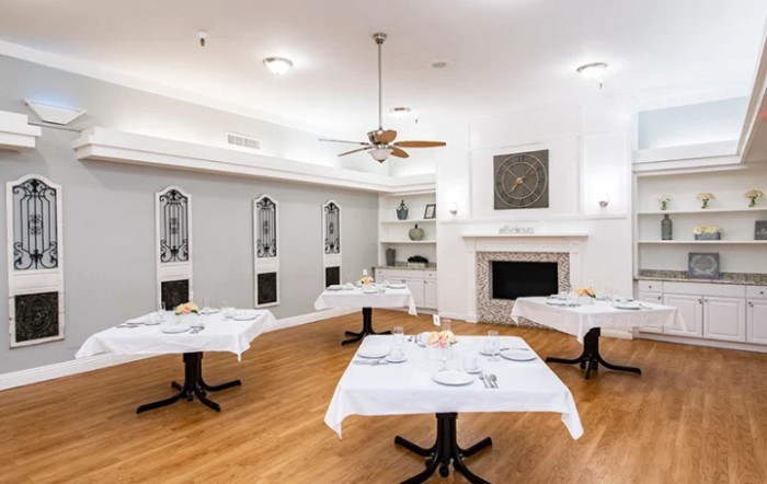 A modern dining room with neatly arranged tables and a cozy fireplace.