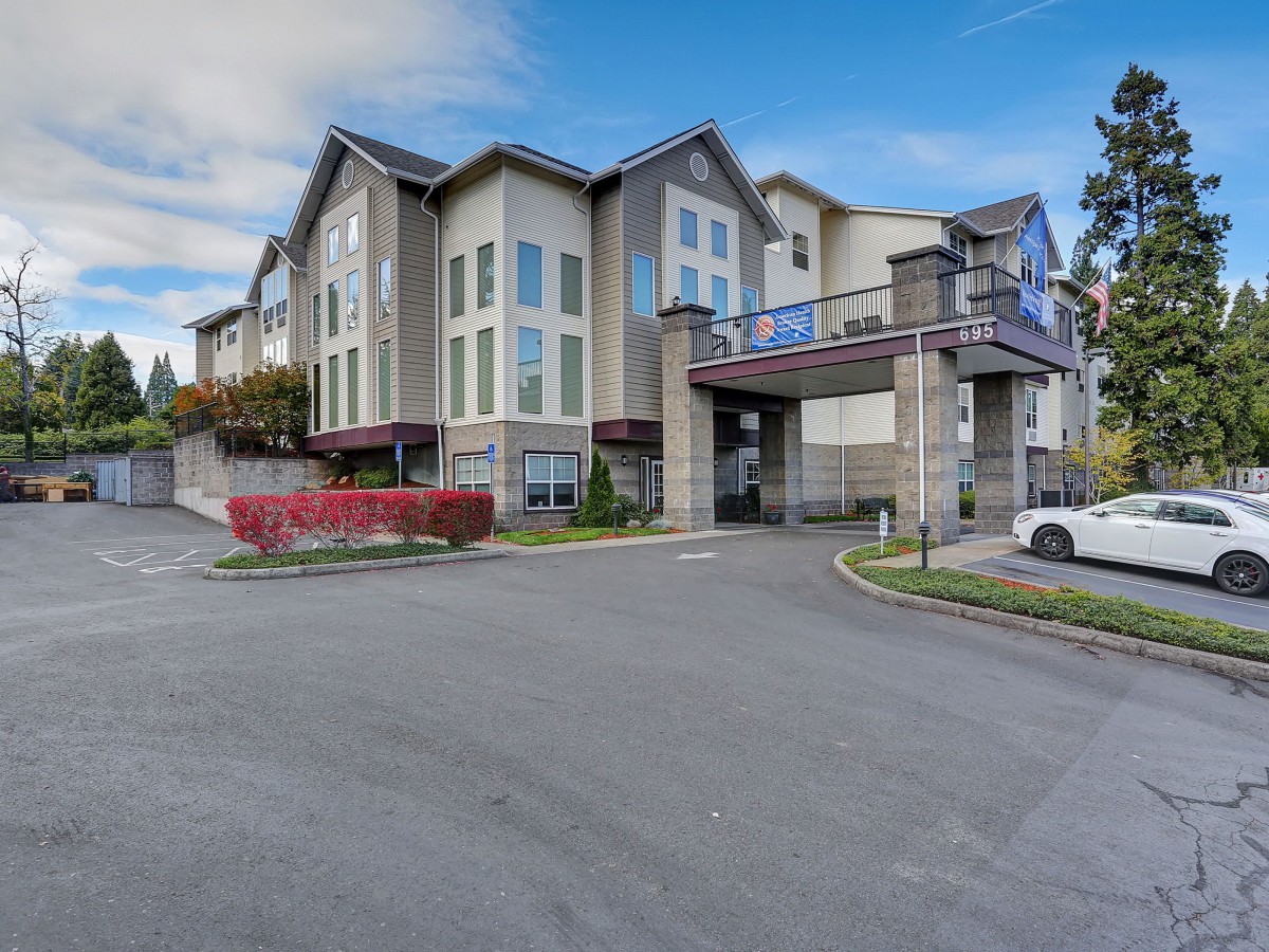 A modern residential apartment complex with a parking area in a suburban setting.