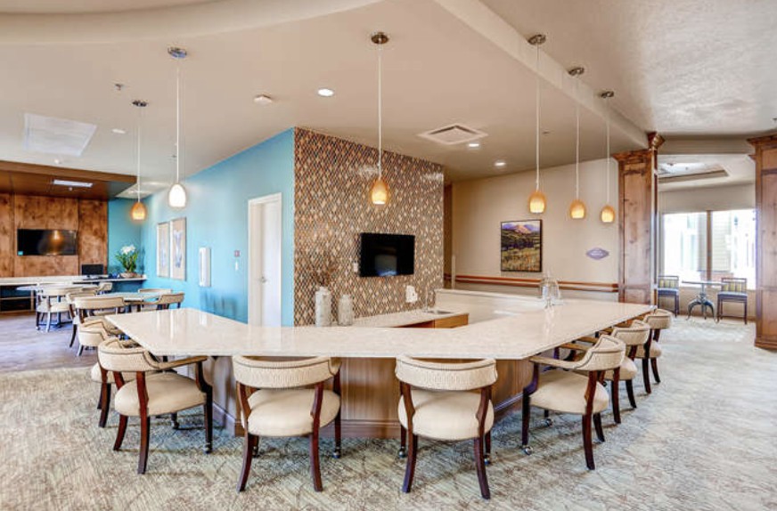 A modern kitchen with a spacious dining area and bar seating, featuring pendant lighting and stylish decor.