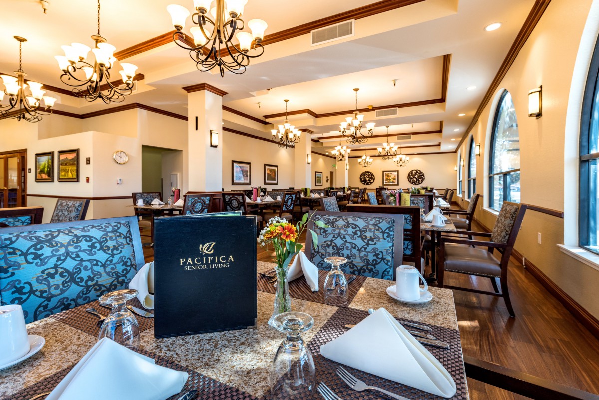 An elegant restaurant dining room with set tables and chandeliers.