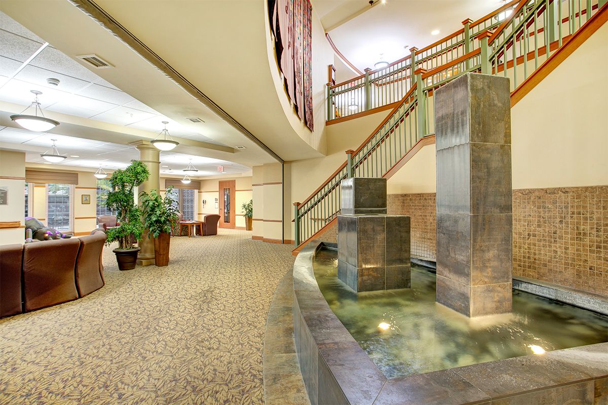 A modern lobby interior with a staircase, water feature, and decorative plants.