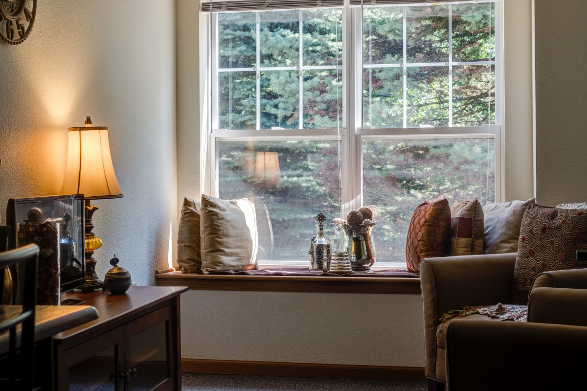 A cozy living room with a large window and cushioned seating area.