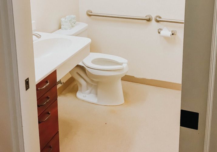 An accessible bathroom with a toilet, sink, and grab bars.