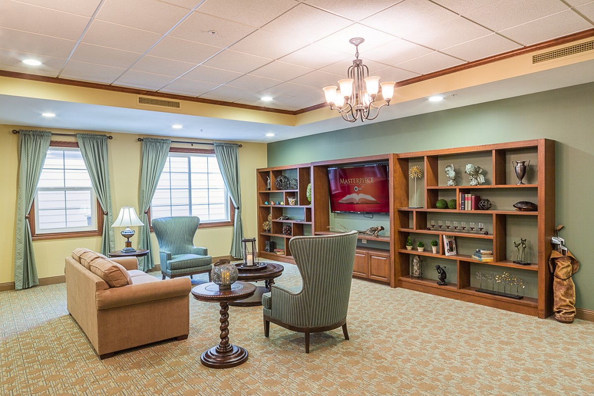 A cozy living room with comfortable seating, bookshelves, and ample lighting.
