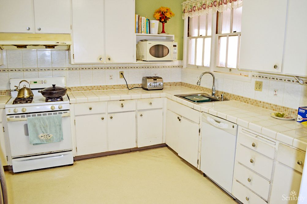 A retro-style kitchen with white cabinets, a microwave, a toaster, and a stove.