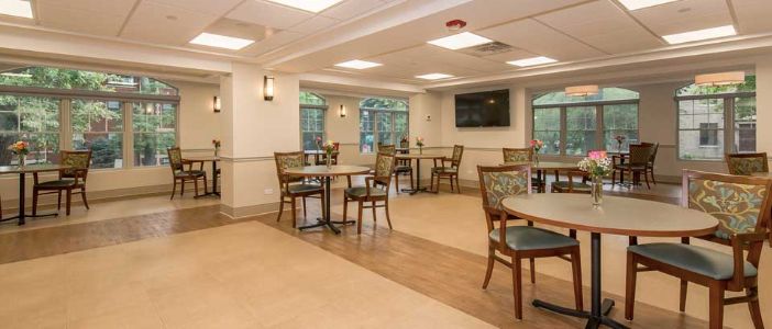 A cozy indoor dining area with tables and chairs, featuring a television on the wall.
