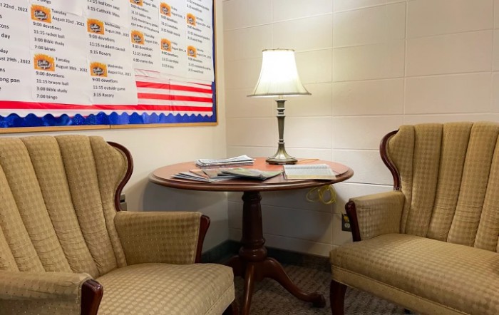 Cozy office waiting area with two chairs, a small table, and a lamp.