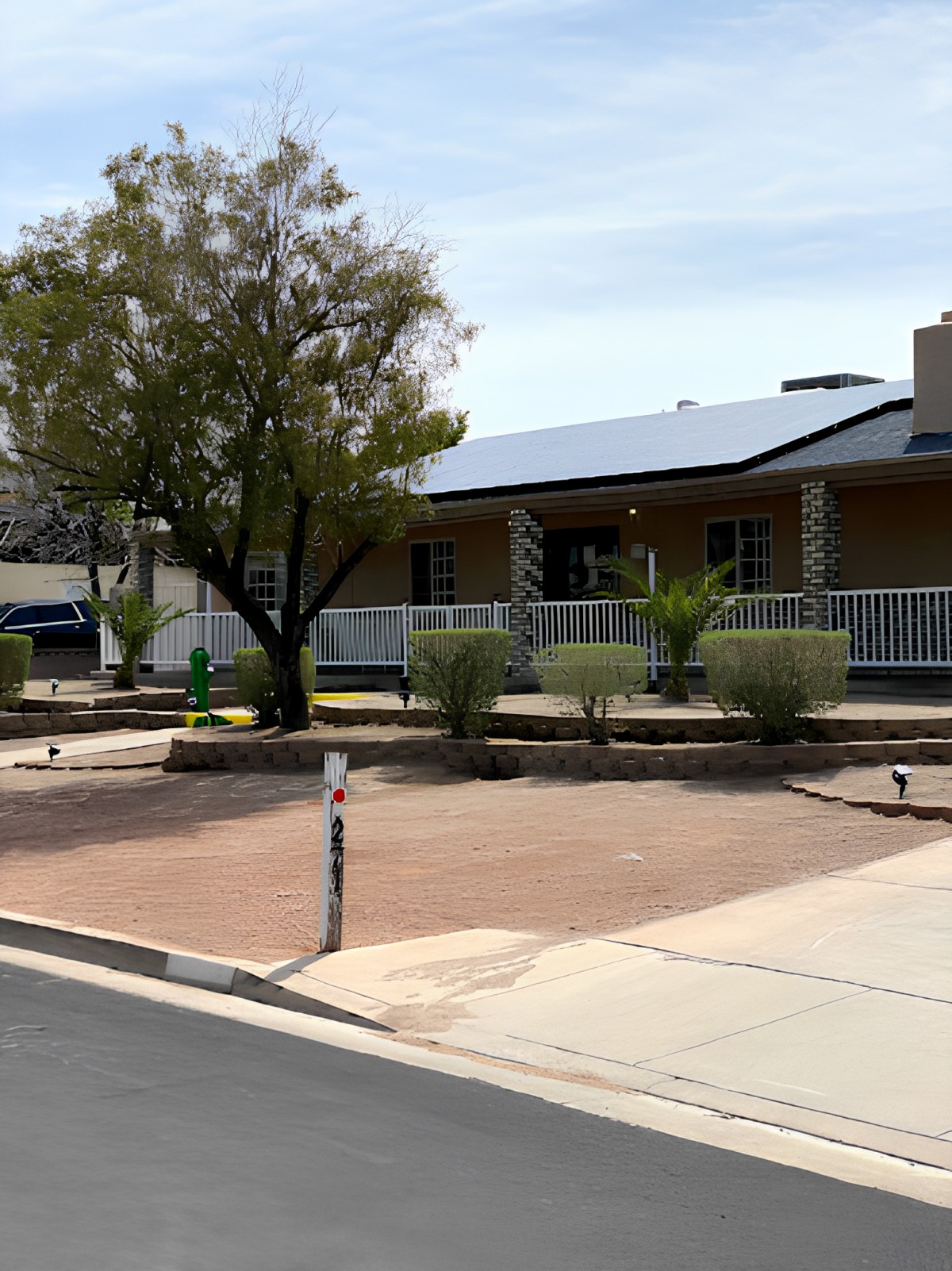 A suburban house with solar panels on the roof and a well-maintained front yard.