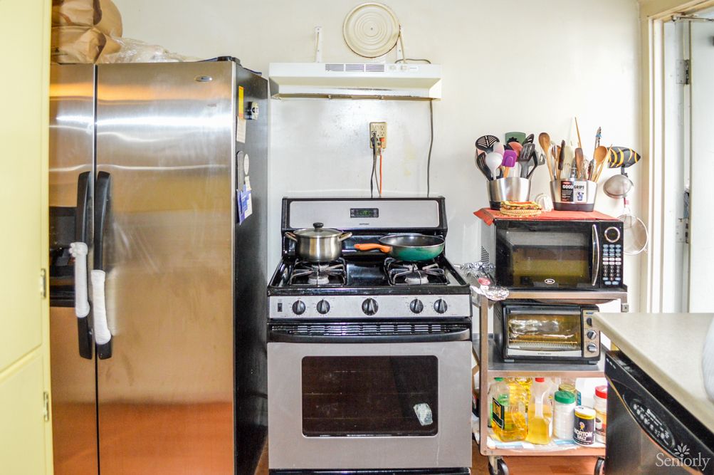 A well-used kitchen featuring a stove with pots, a refrigerator, and various cooking utensils.