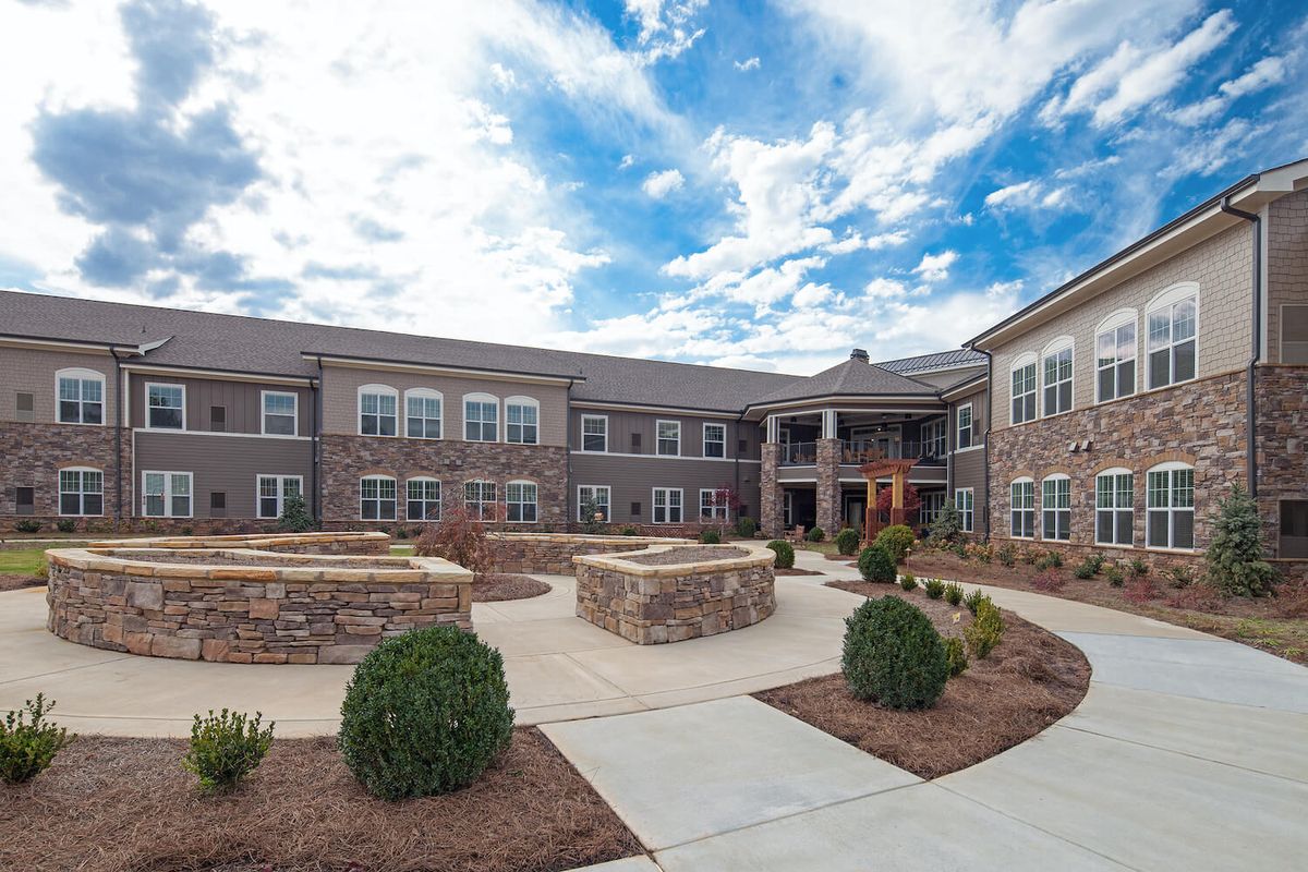 A view of a modern building with a landscaped courtyard under a partly cloudy sky.
