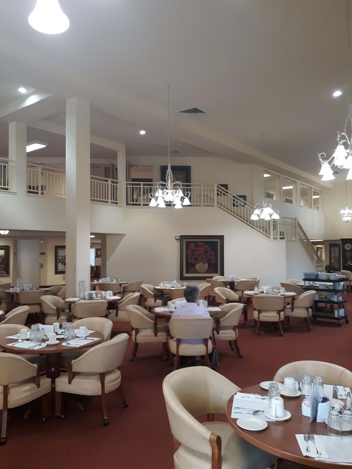 An elegant and spacious restaurant dining area with chandeliers and neatly arranged tables and chairs.