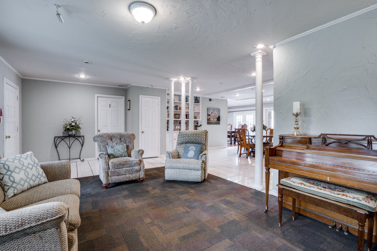 A modern living room with comfortable armchairs and a view into the dining area.