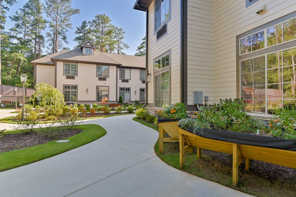 A scenic outdoor view featuring a garden path surrounded by modern buildings.