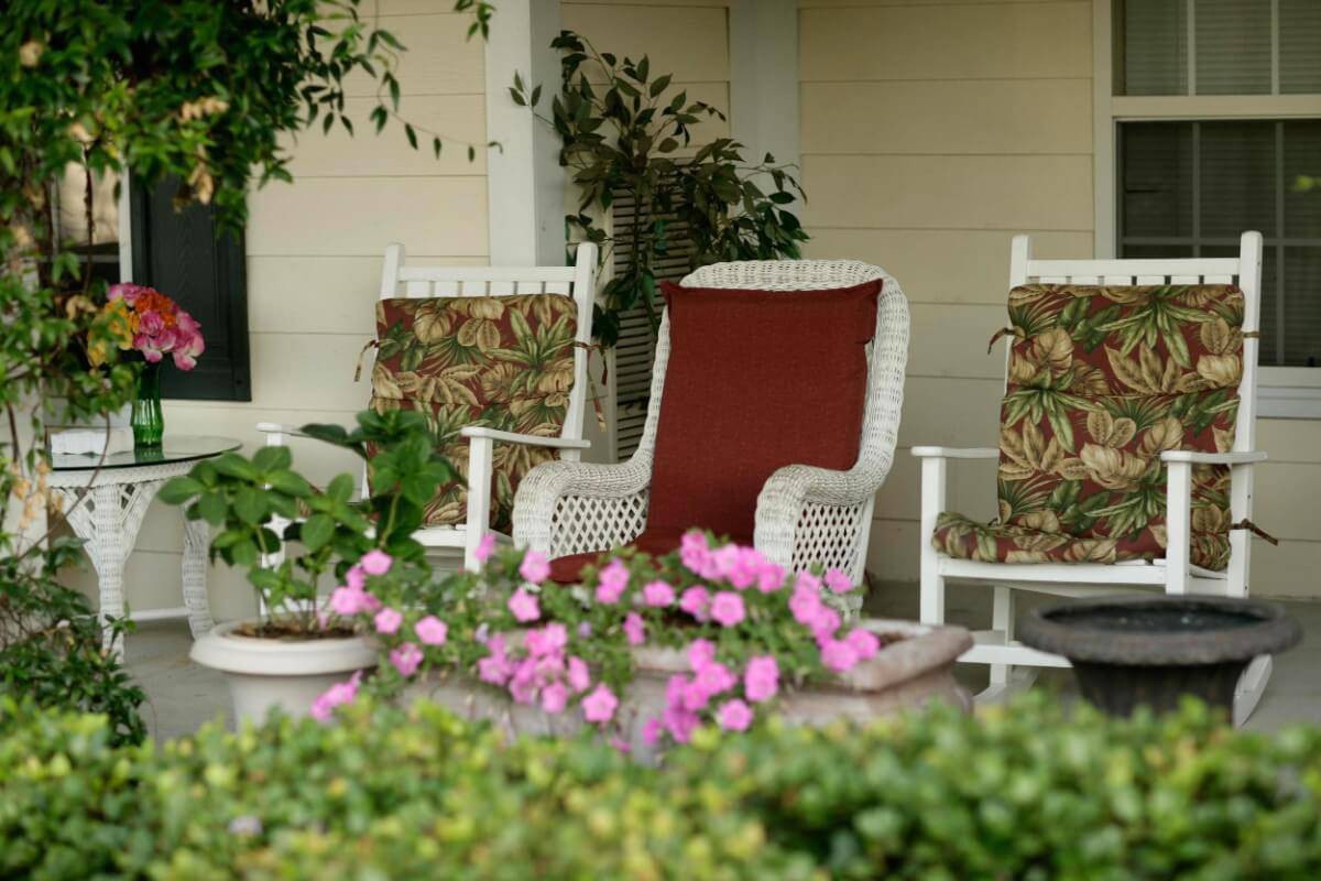 A cozy porch setup with wicker chairs and blooming flowers.