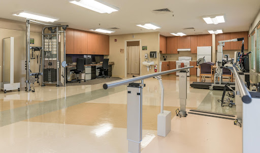 A spacious rehabilitation center featuring exercise equipment, including parallel bars for physical therapy.