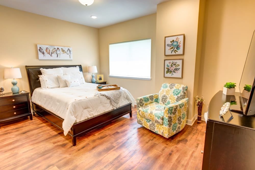 A cozy bedroom with a bed, colorful armchair, and decorative wall art.