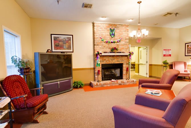 A cozy living room with a brick fireplace and a large television.