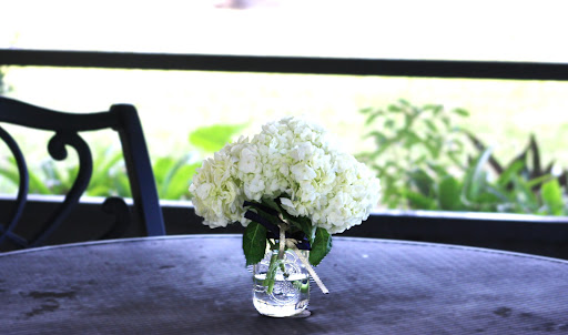 A beautiful arrangement of white hydrangeas in a glass vase, adding a touch of elegance to the outdoor table.