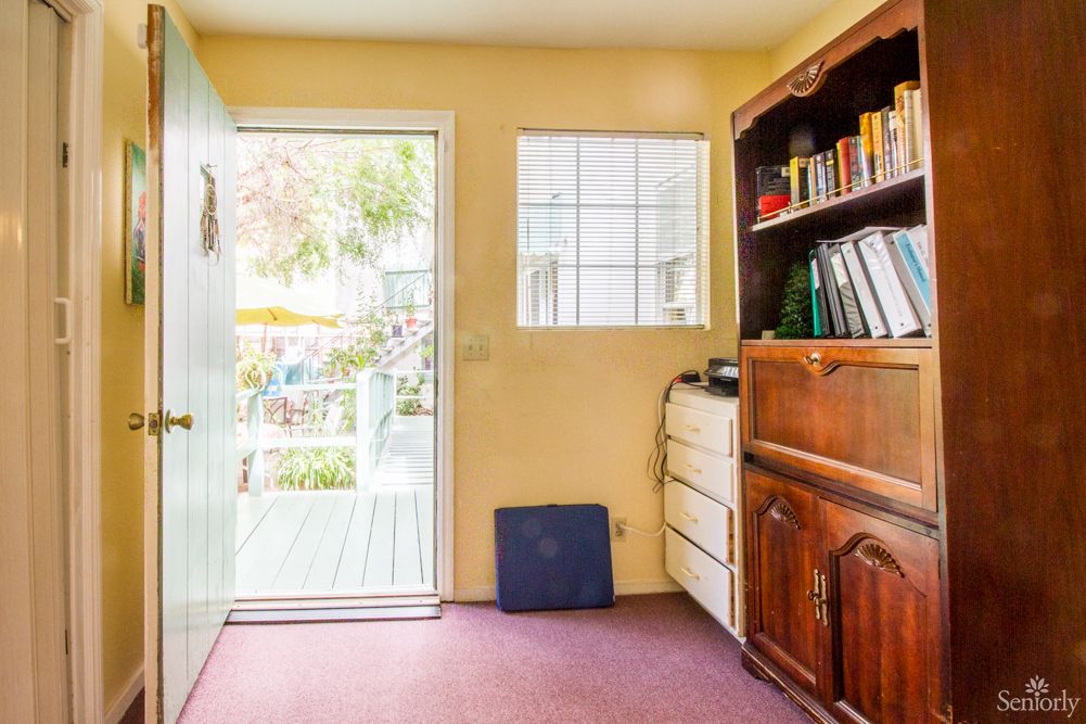 A cozy interior room with a bookshelf and an open door leading outside.