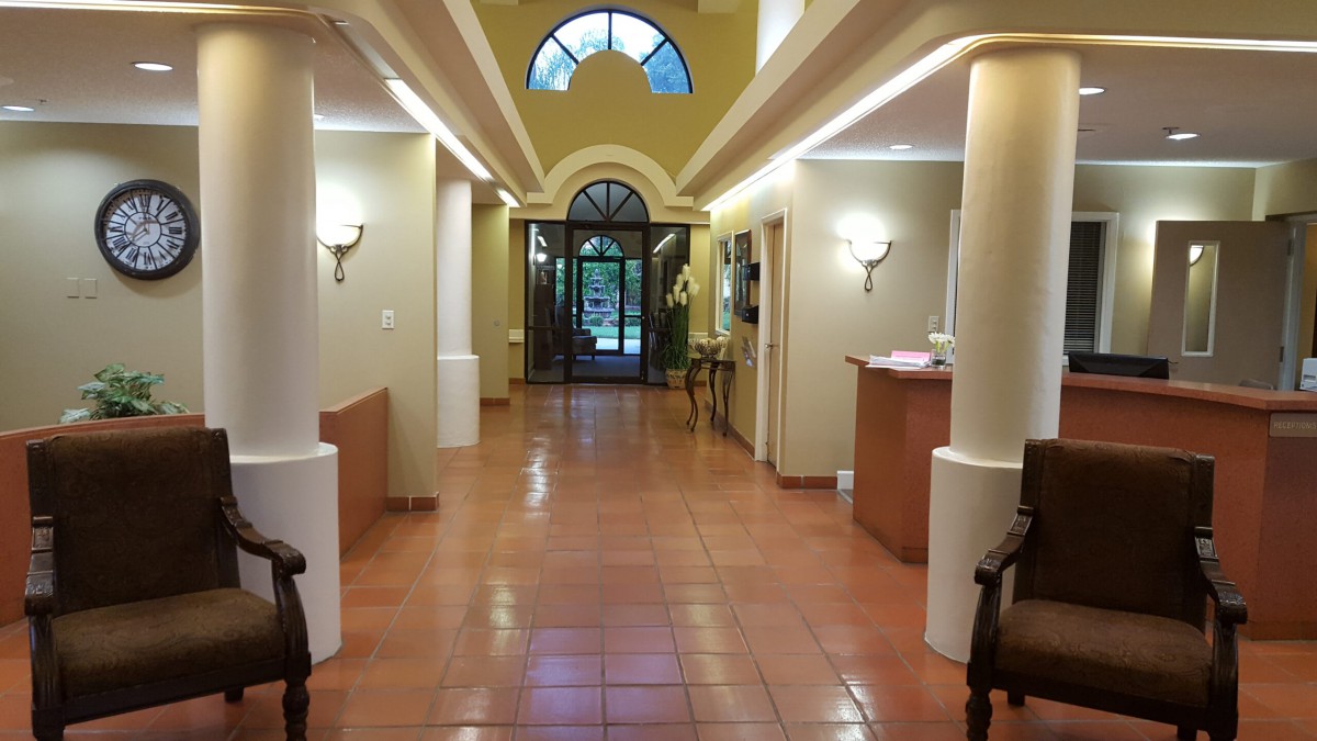 A welcoming hallway with a reception desk, featuring warm lighting and tiled flooring.