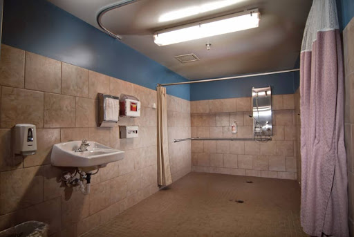 A view of a spacious bathroom featuring tiled walls, a sink, and overhead lighting.