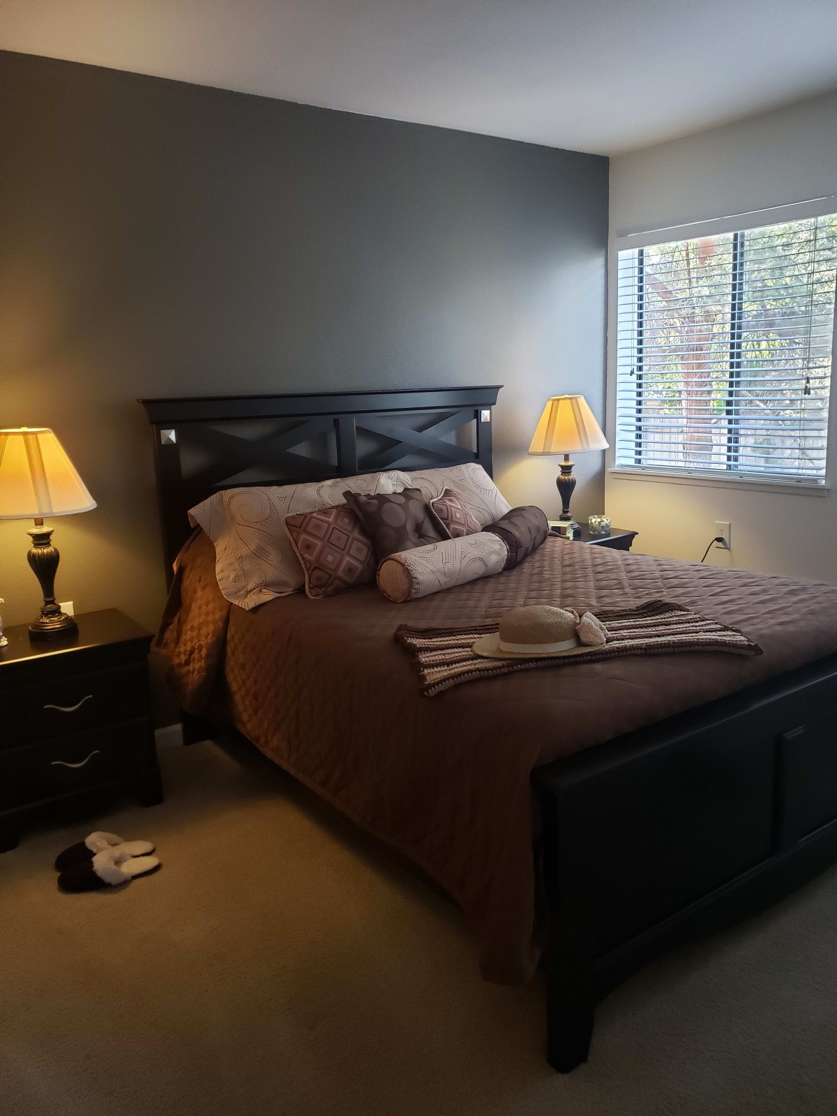 A cozy bedroom with a neatly made bed, complete with decorative pillows and matching lamps on each side.