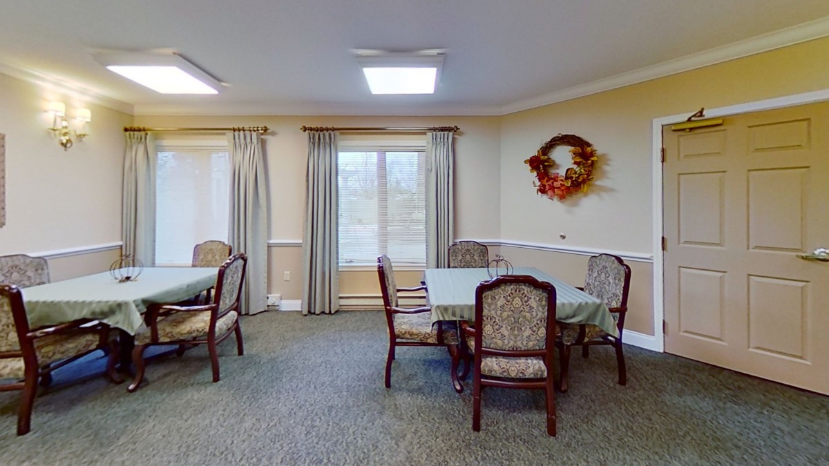 A cozy dining area with tables and chairs, featuring elegant curtains and wall decor.