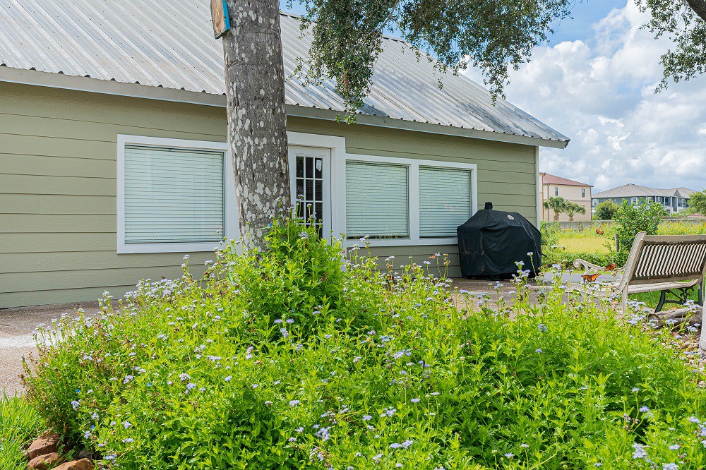A backyard with a green lawn and an outdoor grill next to a house.