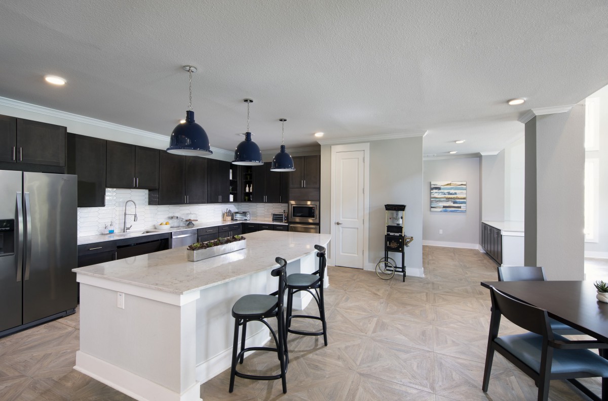 A modern kitchen with a central island, bar stools, and stylish pendant lighting.