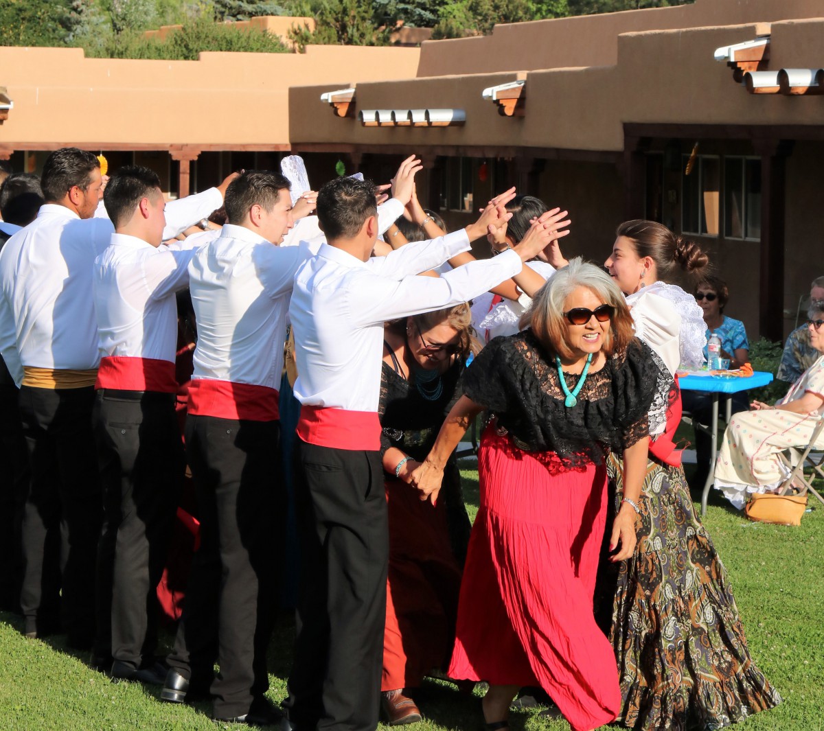 A group of people in traditional clothing dancing and celebrating outdoors.