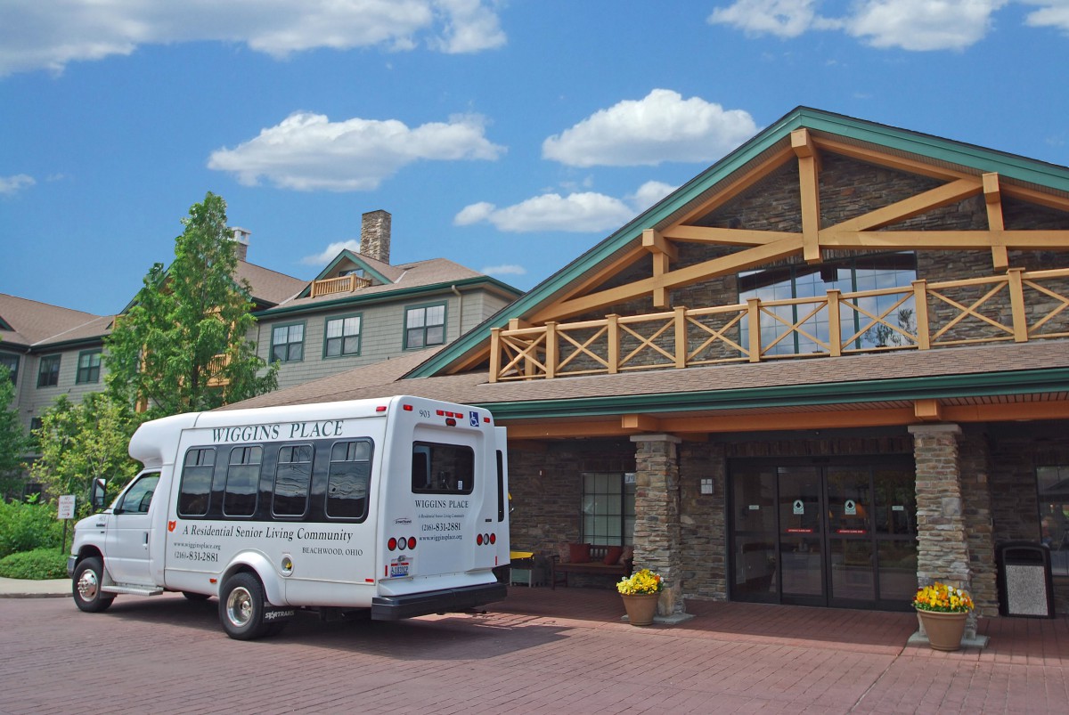 A shuttle bus parked outside a large building with rustic architectural features.