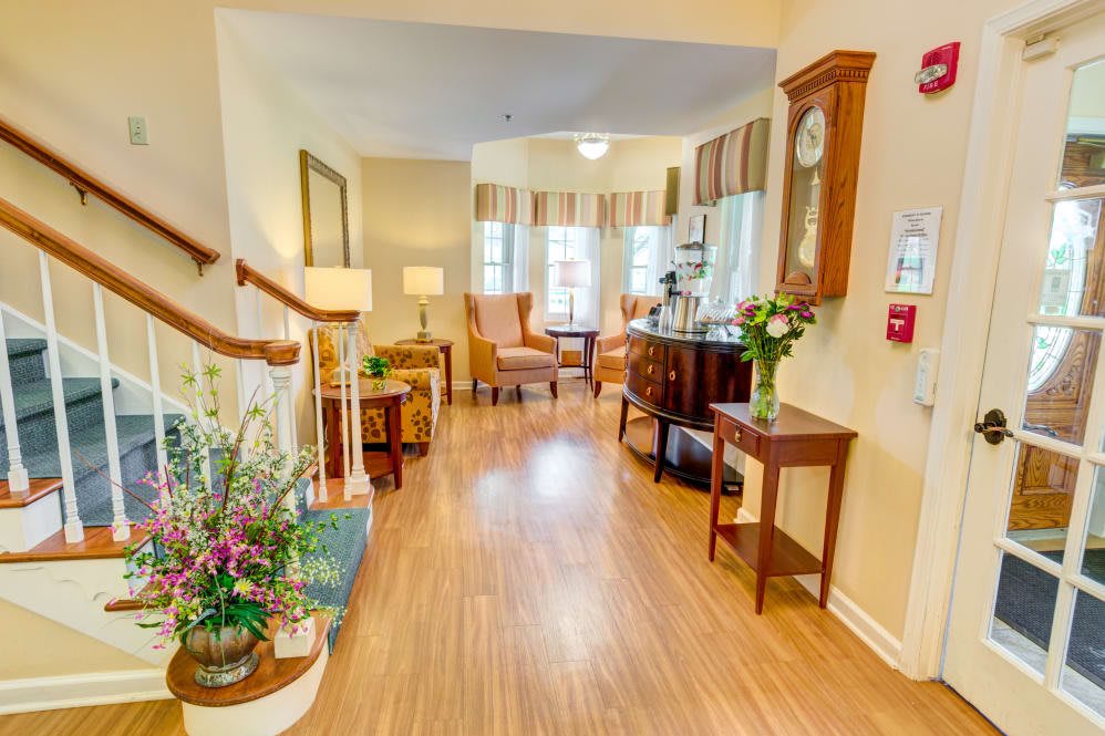 A cozy living space with wooden flooring, elegant furniture, and floral decorations.