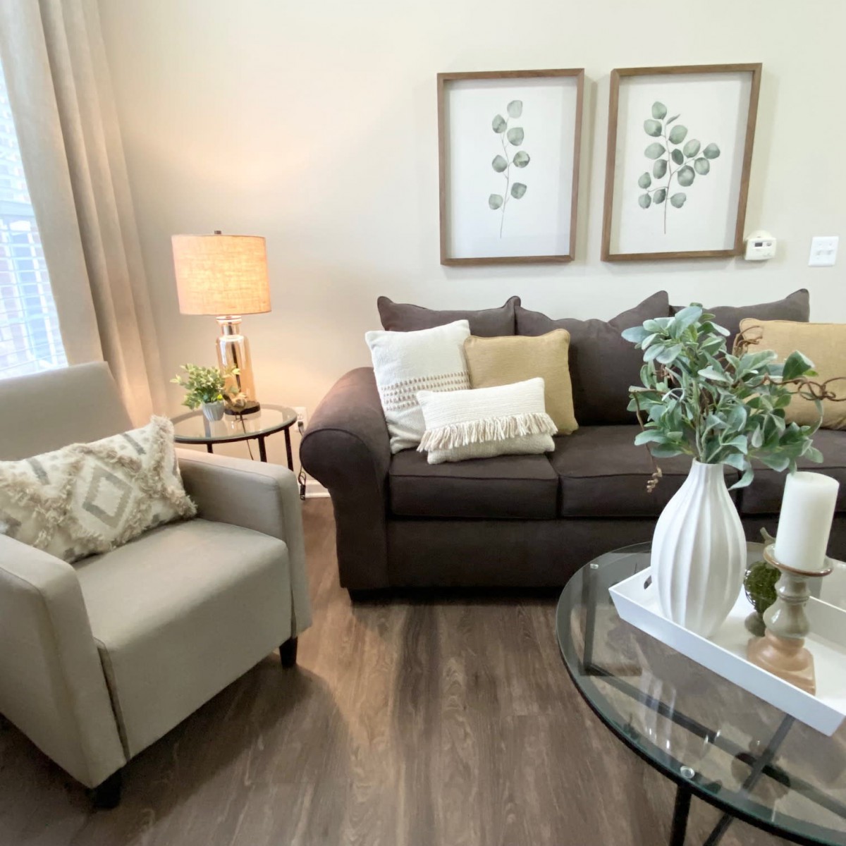 A cozy and well-decorated living room with a brown sofa, beige armchair, and stylish accessories.