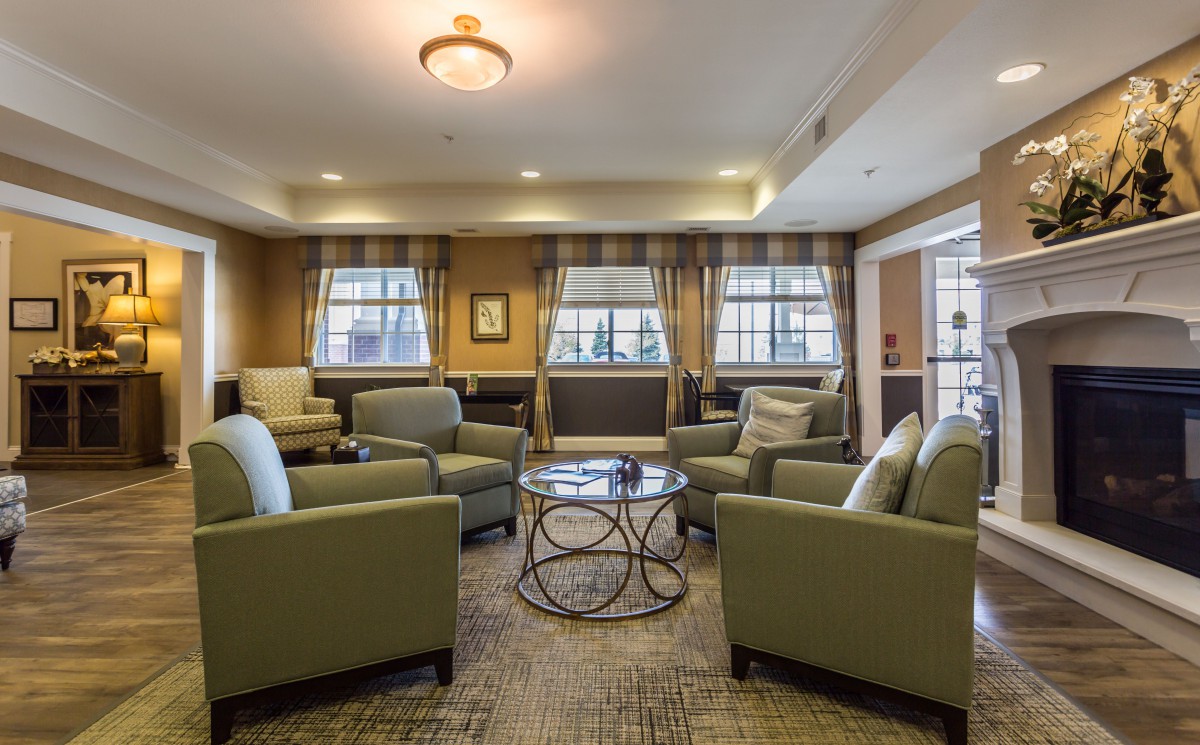 A cozy living room with armchairs arranged around a circular table under soft lighting.