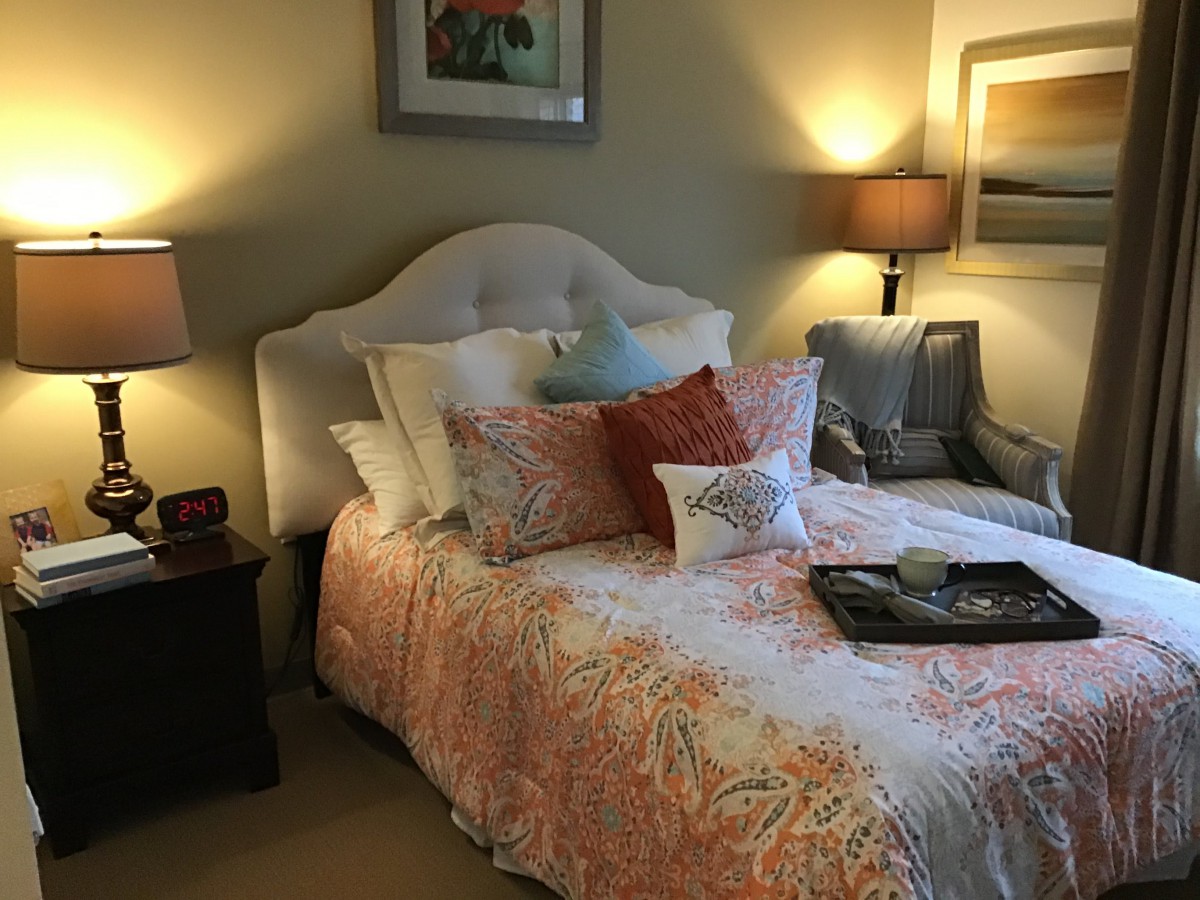 A cozy bedroom with a well-decorated bed and warm lighting.