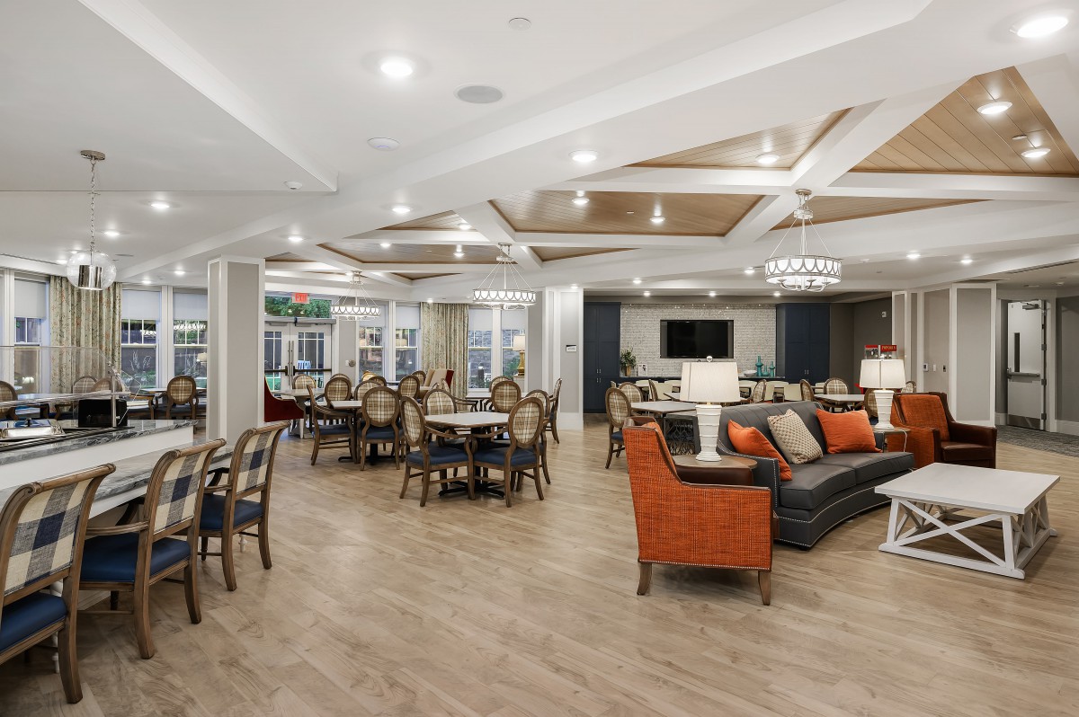 A spacious and modern lounge area featuring dining tables, comfortable seating, and elegant lighting.