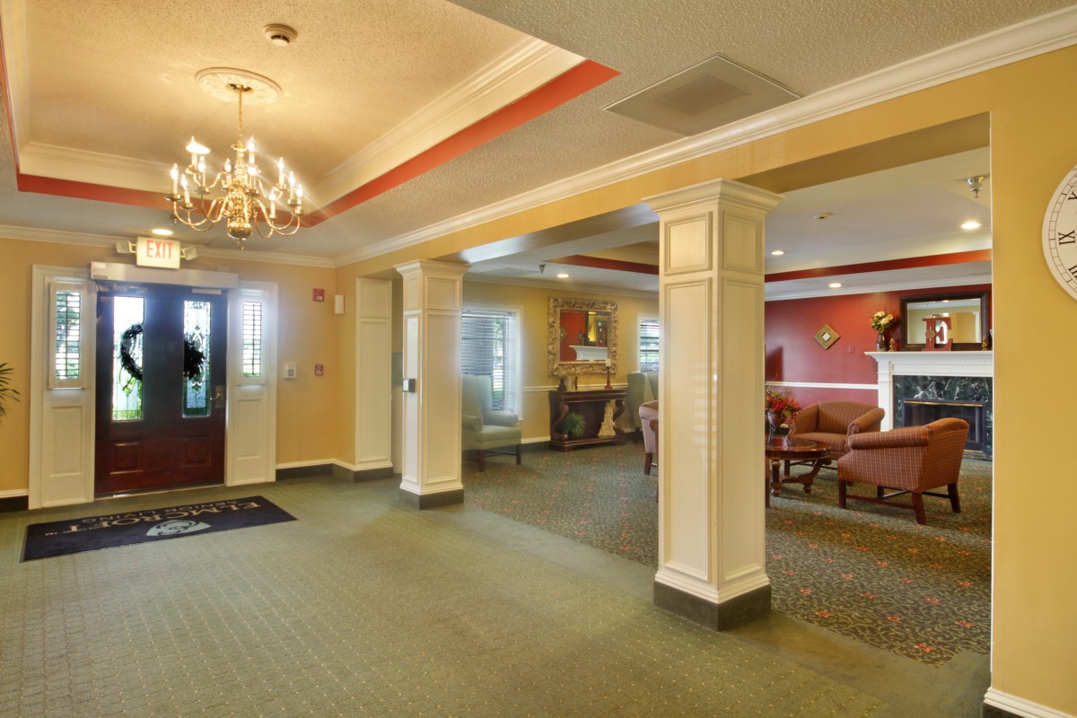 A spacious lobby with elegant columns, a chandelier, and comfortable seating.