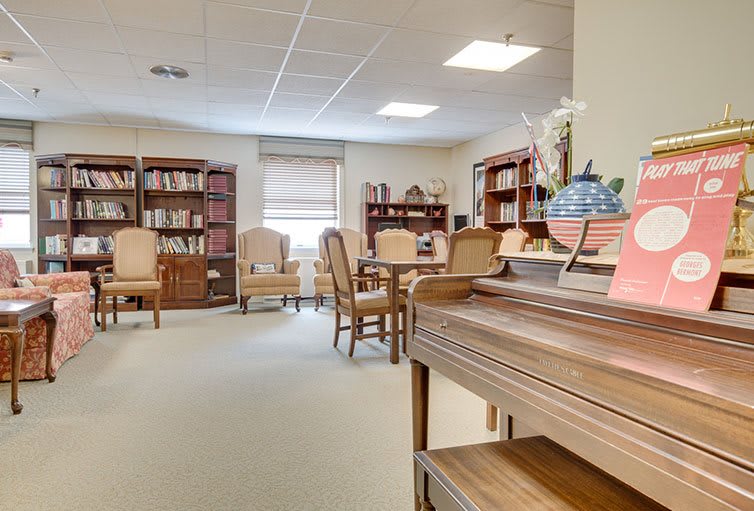 A cozy library reading room with bookshelves, chairs, and a table.