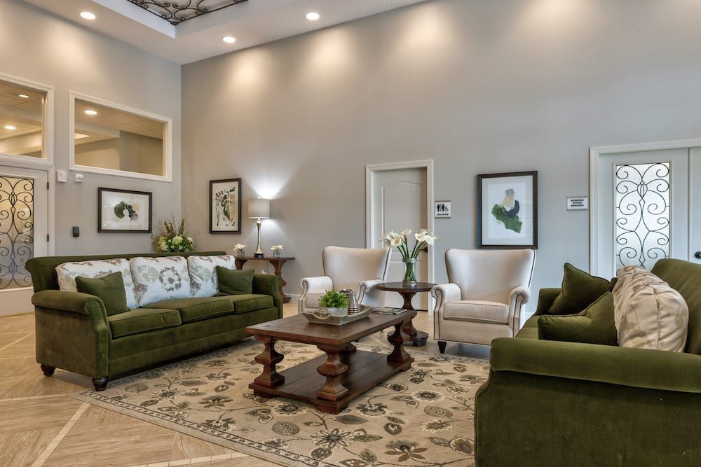 Elegant living room with green sofas, white armchairs, and a wooden coffee table.