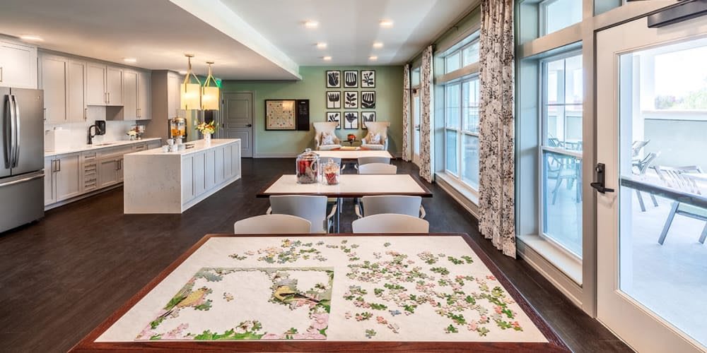 A modern open-plan living room with a puzzle on the table and spacious kitchen area.