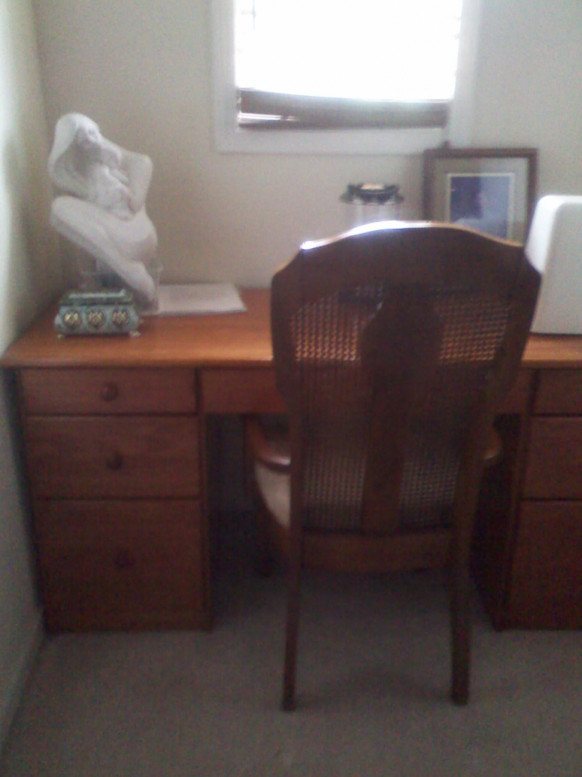 A home office with a wooden desk, chair, and decorative items.