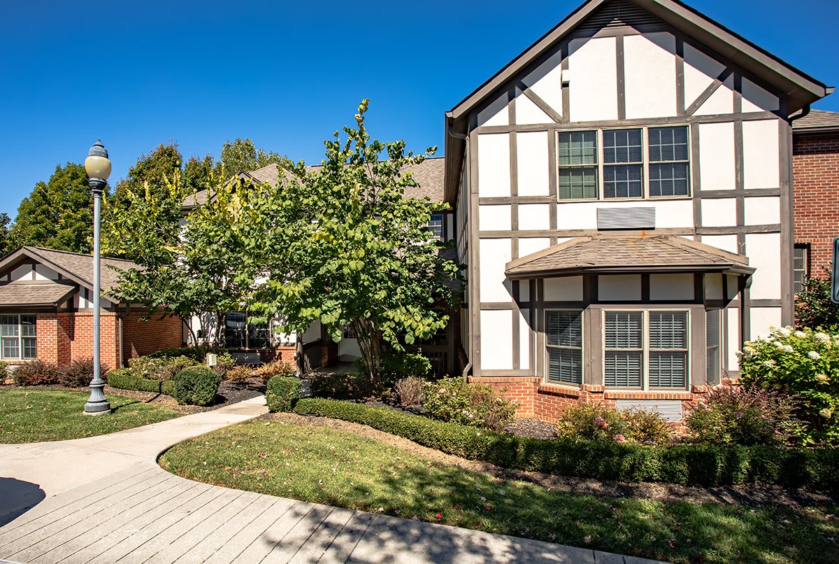 A charming residential house with a mix of brick and wood architecture, surrounded by a well-maintained garden and a paved pathway.